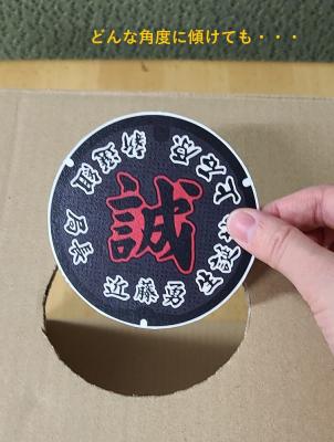 マンホール蓋の模型を傾ける写真