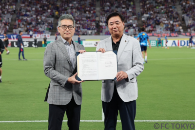 ピッチ上で協定締結書を持った様子