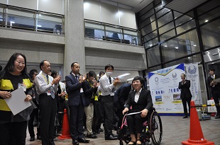 会場から拍手で送られる山崎さんの写真