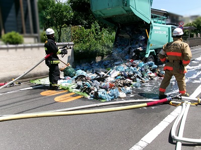 ごみ収集車両の後部を開けて消防隊員による放水が終わったところの画像