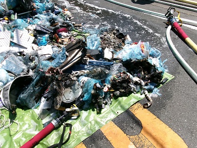 ごみ収集車両の中で燃えたごみを路上に置いている画像